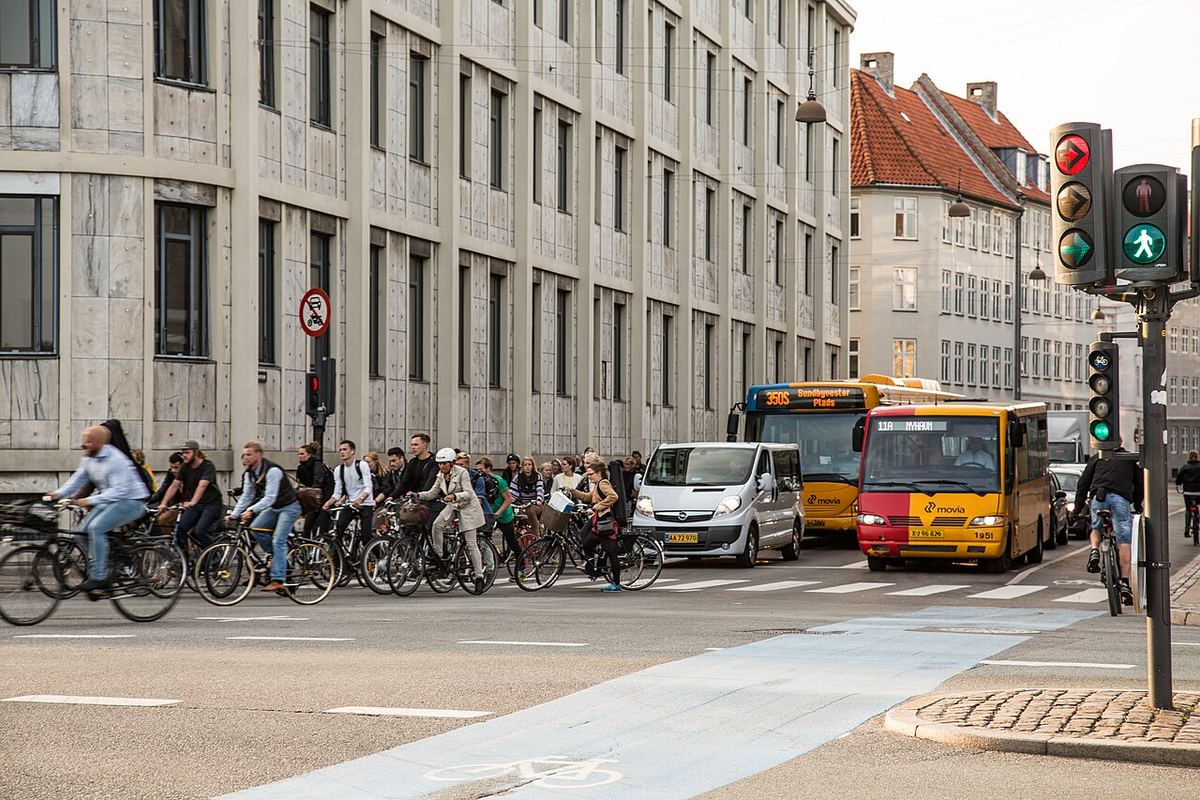 Cykelpendlere venter for rødt i et kryds med blå cykelbane i København
